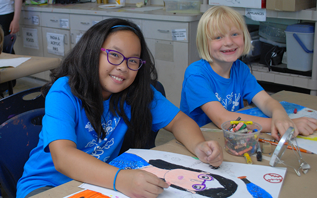 Two girls in blue t-shirts drawing cartoons at Cheekwood's cartoon creations summer camp class